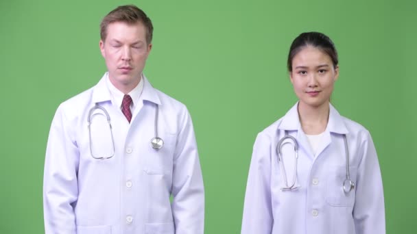 Multi-etnický pár lékařů ukazuje na kameru dohromady — Stock video