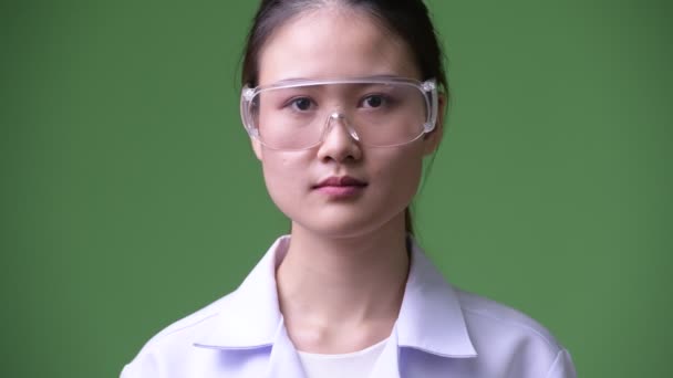 Joven hermosa mujer asiática médico usando gafas protectoras sonriendo — Vídeo de stock