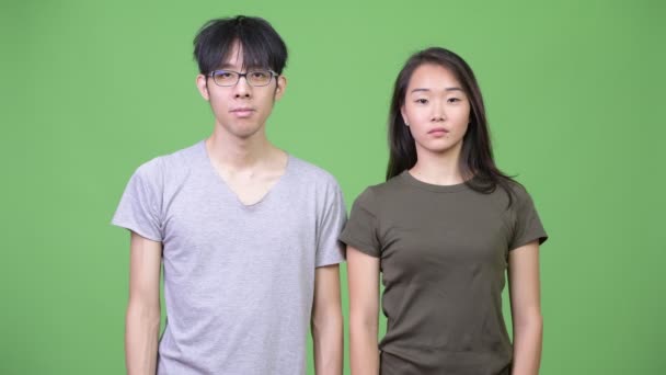 Молодая азиатская пара, указывающая на камеру — стоковое видео