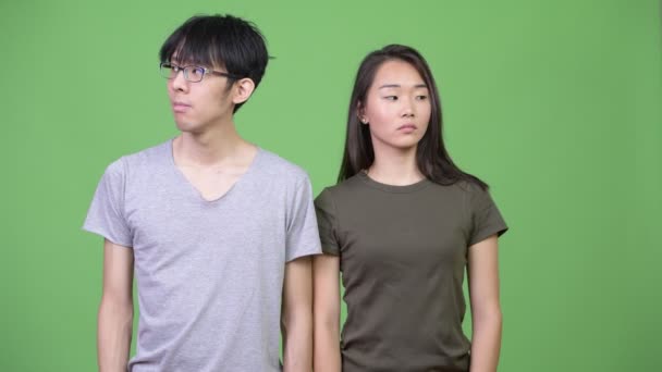 Молодая азиатская пара смотрит в сторону вместе — стоковое видео