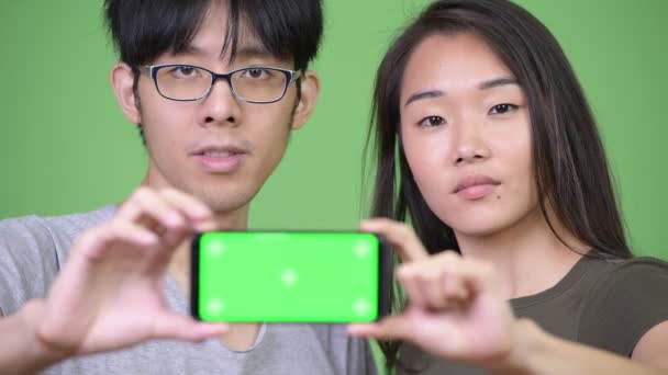 Jeune couple asiatique montrant téléphone ensemble — Video