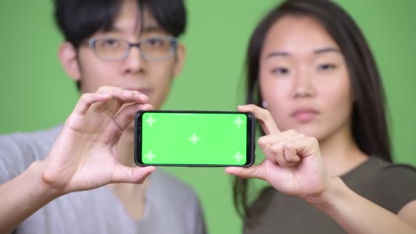 Unga asiatiska par visar telefonen tillsammans — Stockvideo