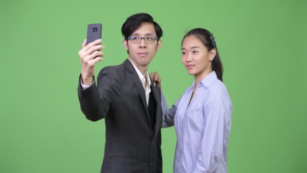 Unga asiatiska företag par använda telefonen tillsammans — Stockvideo