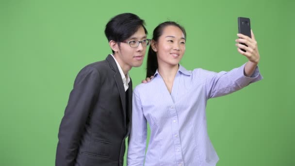 Νεαρά ασιατικές επιχειρήσεις ζευγάρι χρησιμοποιώντας τηλέφωνο μαζί — Αρχείο Βίντεο