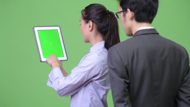 Pár mladých asijských trhů společně pomocí digitálních tabletu — Stock video