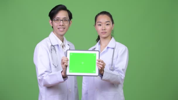 Молодые азиатские врачи показывают вместе цифровой планшет — стоковое видео