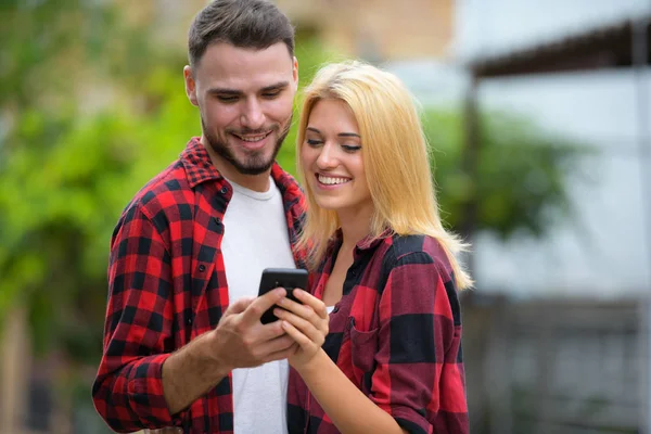 Молода пара використовує телефон разом на вулиці на відкритому повітрі — стокове фото