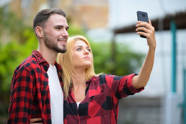 Pareja joven usando el teléfono juntos en las calles al aire libre — Foto de Stock