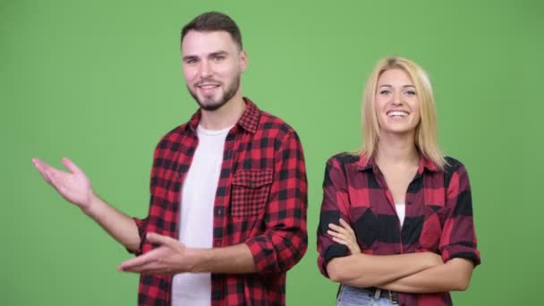 Молодая счастливая пара показывает что-то вместе — стоковое видео