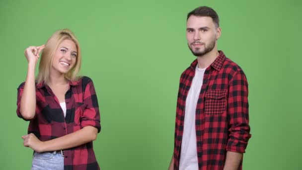 Jeune couple heureux claquer des doigts et montrer quelque chose ensemble — Video
