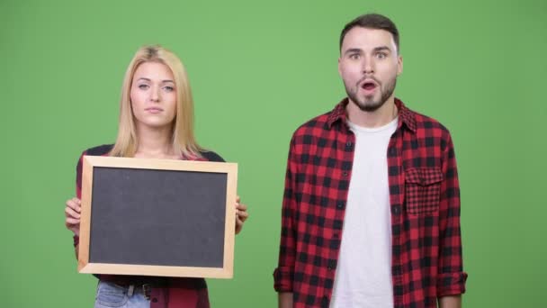 A fiatal pár tábla gazdaság és keresett döbbenve együtt — Stock videók
