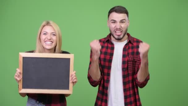 A fiatal pár tábla gazdaság és látszó izgatott együtt — Stock videók