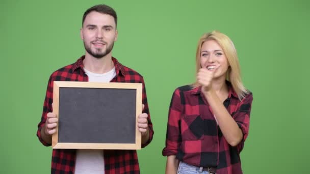 Ungt par hålla blackboard och ger tummen upp tillsammans — Stockvideo