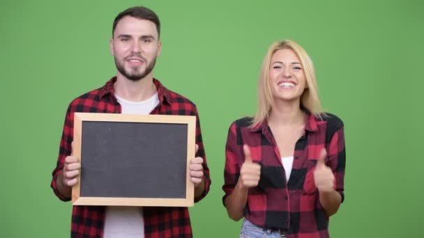 Mladý pár drží tabuli a dává palec nahoru, společně — Stock video