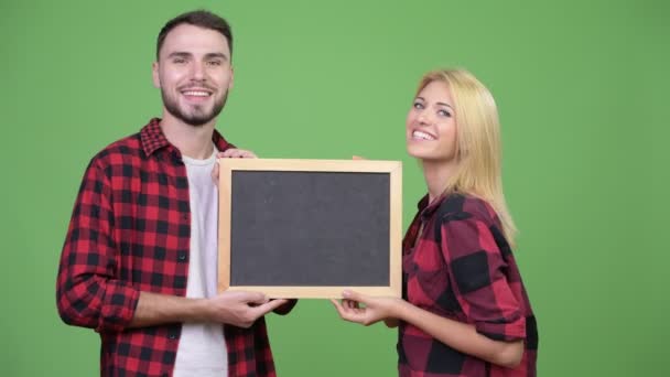 Молодая счастливая пара держит доску вместе — стоковое видео