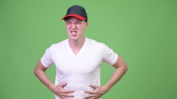Mladý pohledný skandinávské muž s bolesti žaludku před zeleným pozadím — Stock video