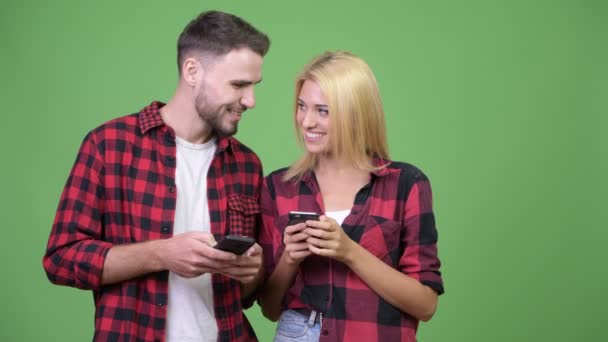 Молодая счастливая пара улыбается, используя телефон вместе — стоковое видео