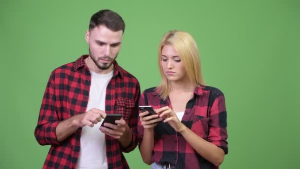 Pareja joven usando el teléfono y mirando sorprendidos juntos — Vídeos de Stock