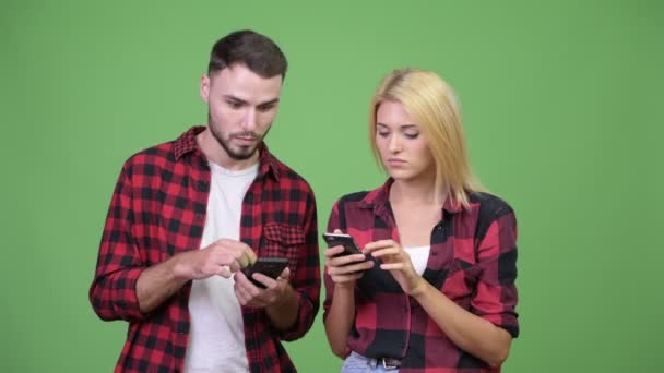 Jeune couple utilisant le téléphone et l'air choqué ensemble — Video