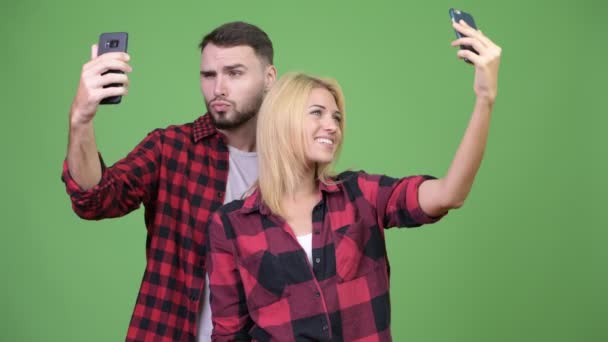 Pareja joven usando el teléfono y tomando selfies juntos — Vídeo de stock