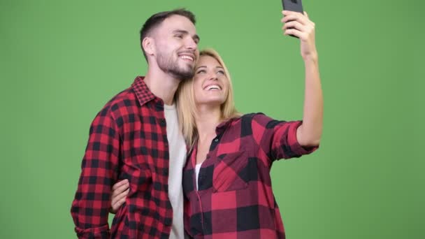 Jong stel met behulp van de telefoon en het nemen van selfies samen — Stockvideo