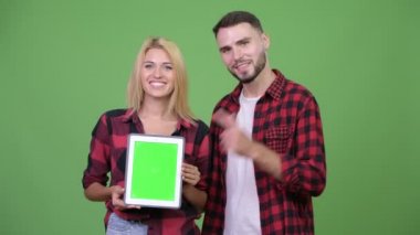 Dijital tablet birlikte gösterilen ve veren genç çift başparmak yukarıya