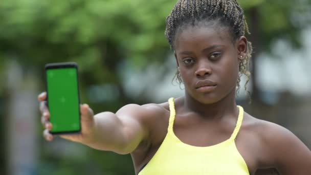 Jeune femme africaine heureuse montrant le téléphone à l'extérieur — Video