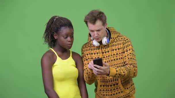 Jeune couple multi-ethnique utilisant le téléphone ensemble — Video