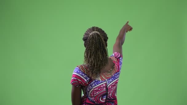 Вид сзади на молодую африканскую женщину, указывающую пальцем — стоковое видео