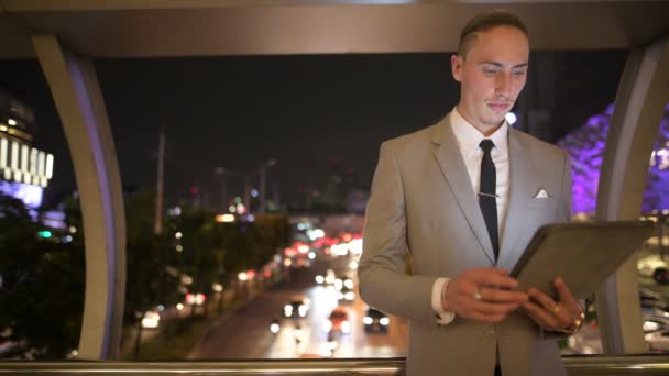 Бизнесмен на открытом воздухе ночью с помощью цифрового планшета — стоковое видео