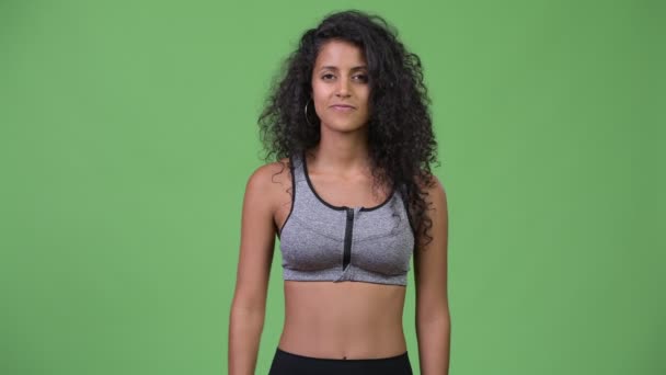 Ung vacker spansktalande kvinna med träningskläder som pekar uppåt — Stockvideo