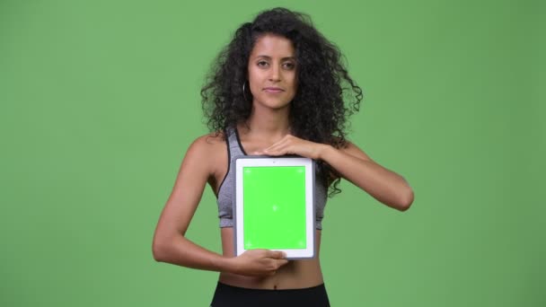 Young beautiful Hispanic woman with gym clothes showing digital tablet — Stock Video