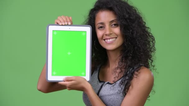 Jovem bela mulher hispânica com roupas de ginástica mostrando tablet digital — Vídeo de Stock