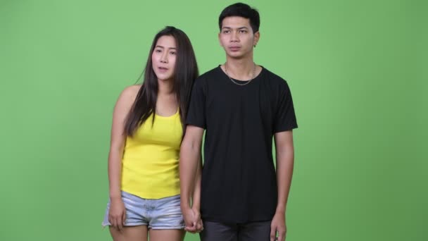 Joven pareja asiática pensando mientras se toma de la mano — Vídeo de stock