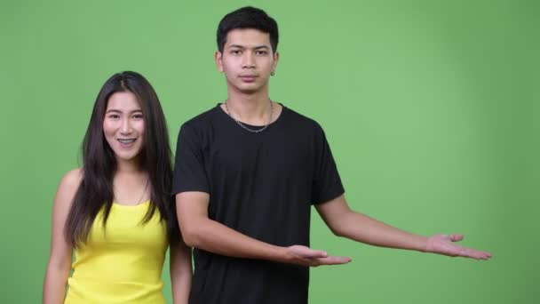 Joven pareja asiática mostrando algo juntos — Vídeos de Stock