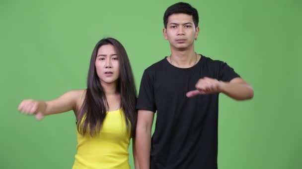 Молодая грустная азиатская пара подает большие пальцы вместе — стоковое видео