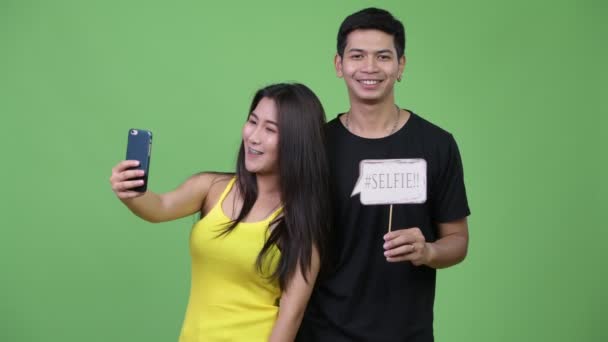 Young happy Asian couple taking selfie together — Stock Video