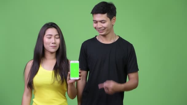 若いアジアのカップル表示電話一緒に — ストック動画