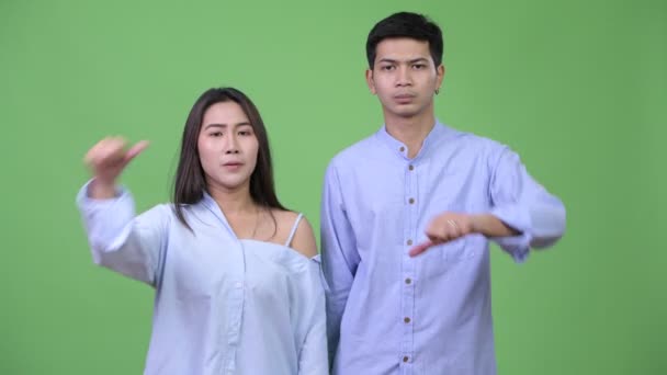 Молодая злая азиатская бизнес-пара подает большие пальцы вместе — стоковое видео