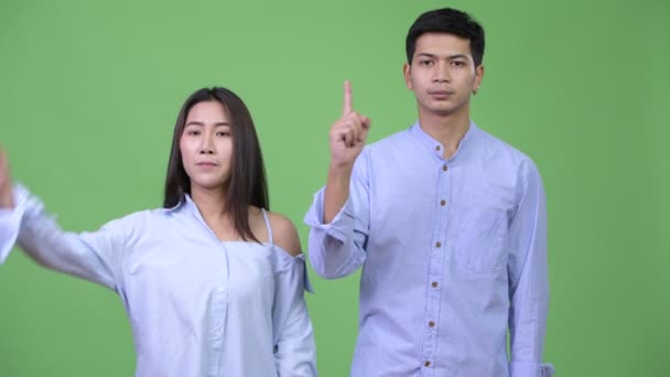 Молодая азиатская пара, указывающая пальцем друг на друга — стоковое видео