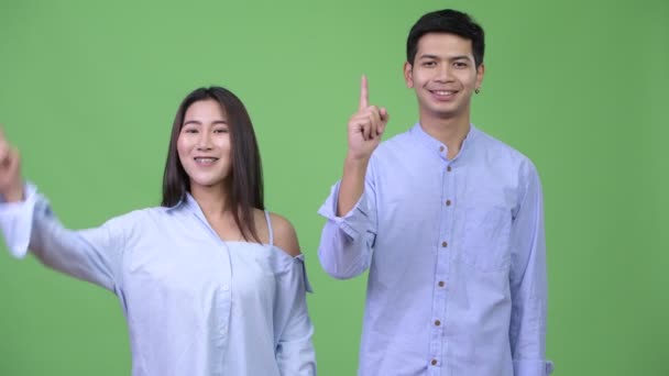 Jonge gelukkig Aziatische business paar wijzende vinger omhoog samen — Stockvideo