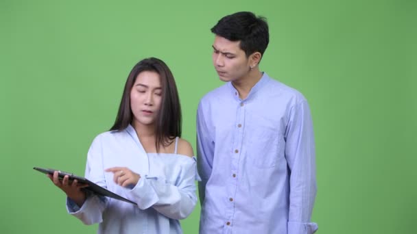 Fiatal ázsiai üzleti pár olvasó-on csipeszes írótábla együtt — Stock videók