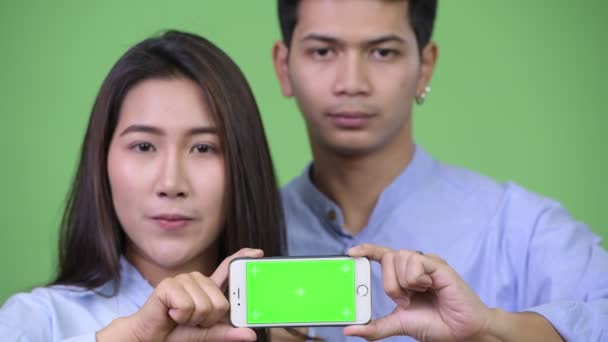 Jovem feliz asiático casal de negócios mostrando telefone juntos — Vídeo de Stock