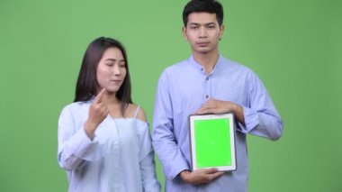 Dijital tablet gösterilen ve Yaşasın vererek genç mutlu Asya iş çift
