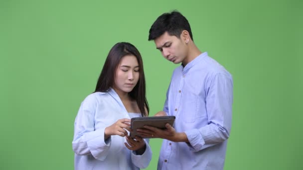 Молодая азиатская бизнес-пара, использующая цифровой планшет и получающая плохие новости вместе — стоковое видео