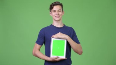 Genç yakışıklı çocuk dijital tablet gösteriyor