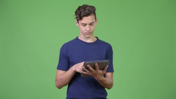 Fiatal jóképű tizenéves fiú, digitális tábla használata — Stock videók