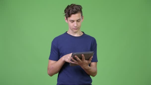 Jovem adolescente bonito usando tablet digital — Vídeo de Stock