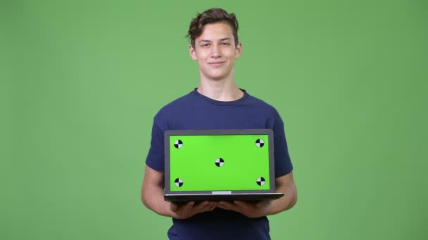 Unga stiliga tonårspojke visar laptop — Stockvideo