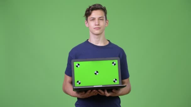 Unga stiliga tonårspojke visar laptop — Stockvideo